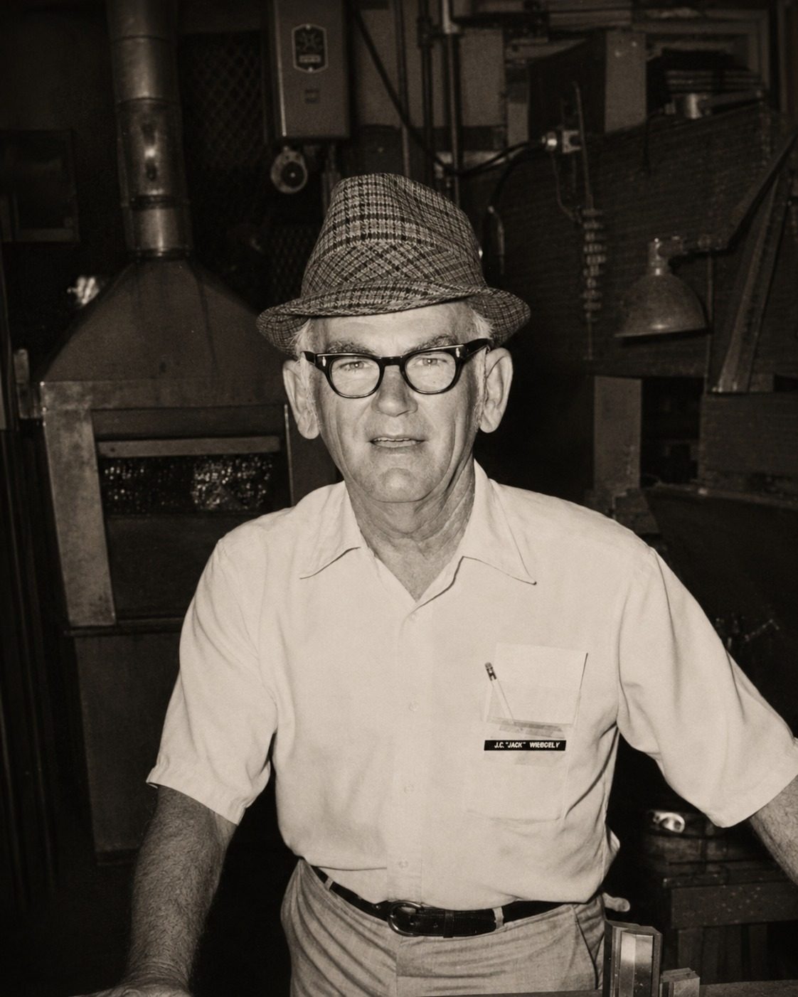 Jack Wimberly in a workshop surrounded by industrial tools and heavy machinery, Hughes Tool Company, Houston, Texas.